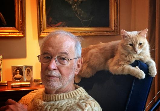 professor in sweater with cat on armchair