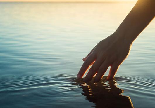 Photo of hand touching a pool of water