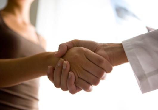 A patient and a doctor shaking hands