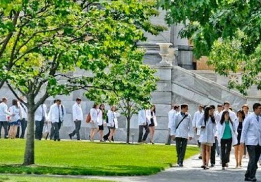 Students in white coats walk on the quad