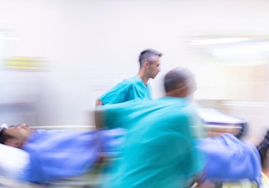 Medical staff hurry through a hospital with a patient on a gurney.