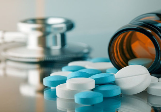 Pills spilling from bottle with stethoscope in background