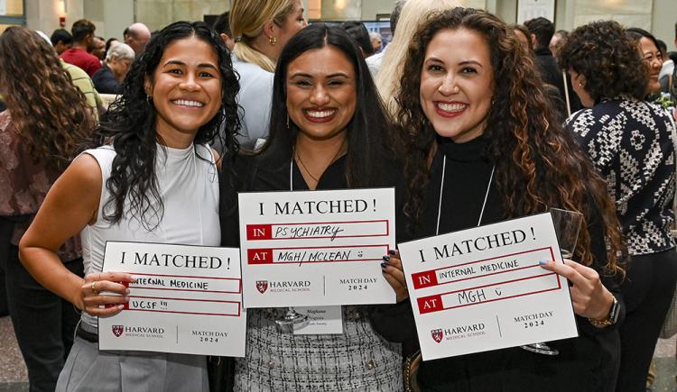 Three grinning students with long hair hold signs that say "I Matched!" with details of where they will pursue their residency training