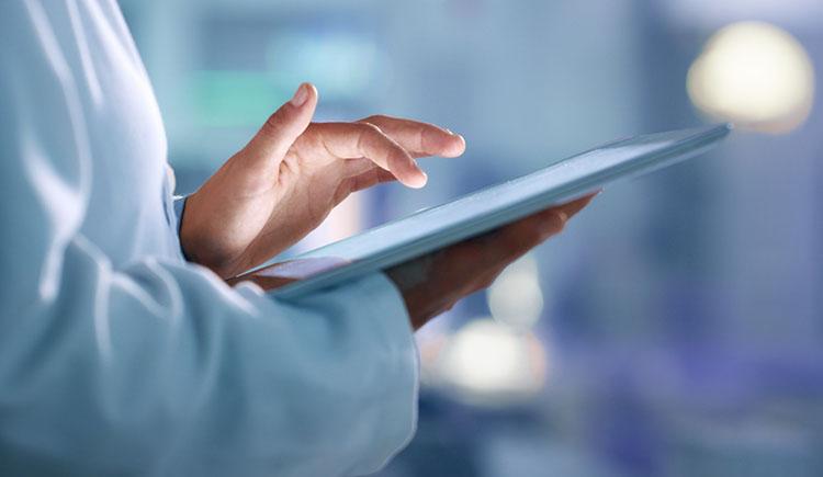 Health care professional wearing a white coat uses a tablet