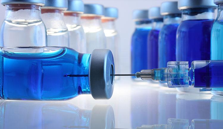 A close-up of glass containers with liquid medication and a syringe