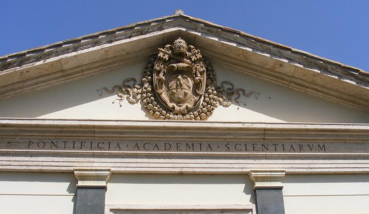The front of a marble building has an intricate carved seal and the words "Pontificia Academia Scientiarum"