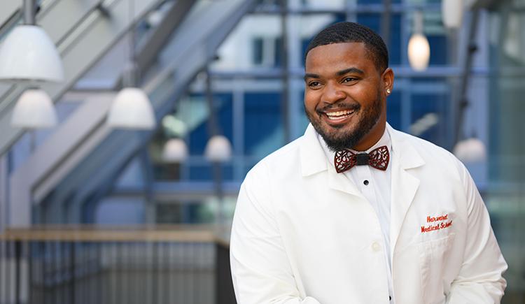 smiling young man in a bow tie and HMS white coat