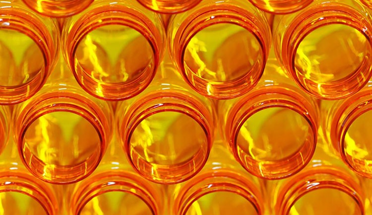 A stack of open orange prescription medicine bottles, glowing with backlight and lightning-shaped highlights.