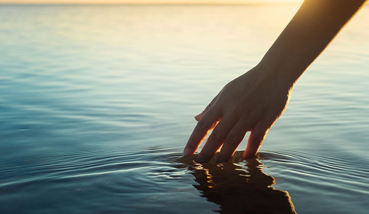 Photo of hand touching a pool of water