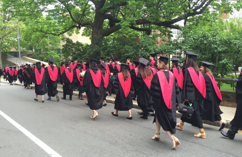HMS MD grads walking in procession, in caps & gowns, from behind