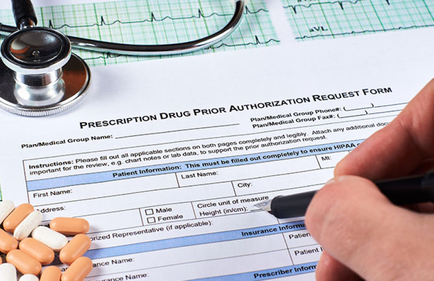 Photo of hand filling out a form, labeled "Prescription Drug Prior Authorization Form."
