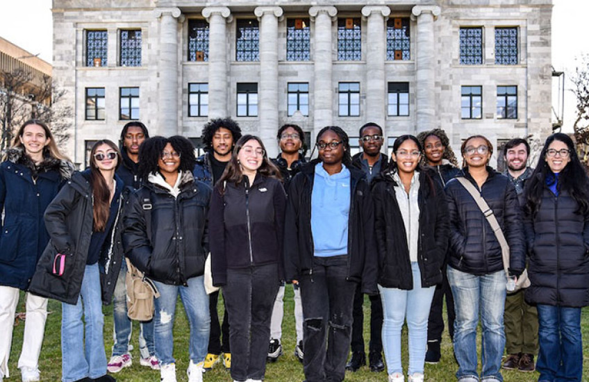 Group of high school students and instructors standing on the lawn in front of Gordon Hall