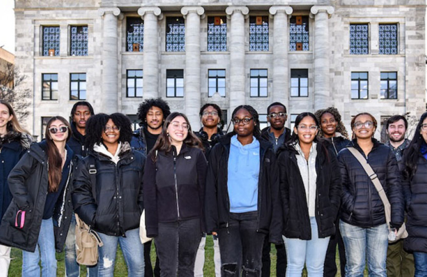 Group of high school students and instructors standing on the lawn in front of Gordon Hall