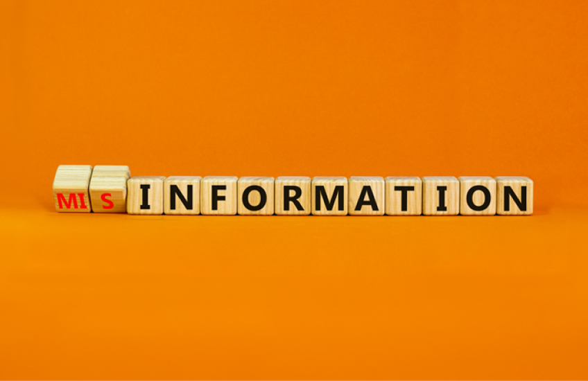 Children's blocks reading "misinformation" on an orange background