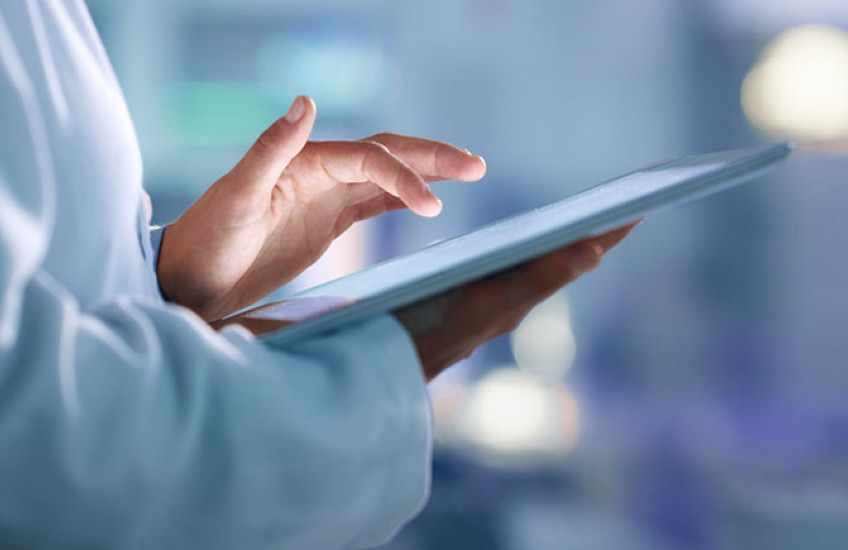 Health care professional wearing a white coat uses a tablet