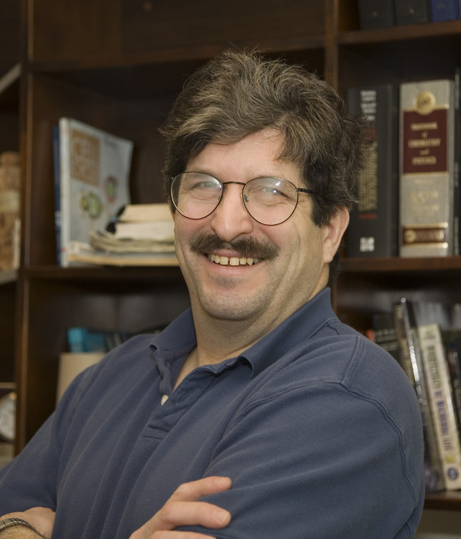Head shot of a smiling man in front of a bookcase