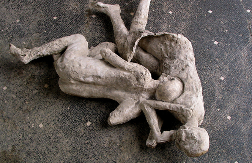 Plaster casts of two figures entangled on a tile floor