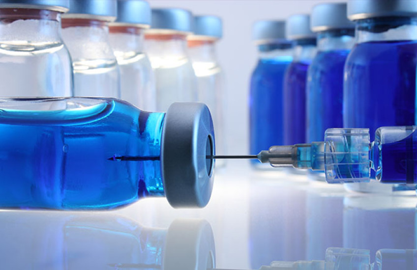 A close-up of glass containers with liquid medication and a syringe