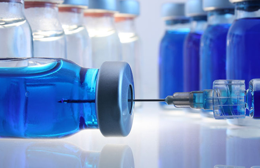 A close-up of glass containers with liquid medication and a syringe