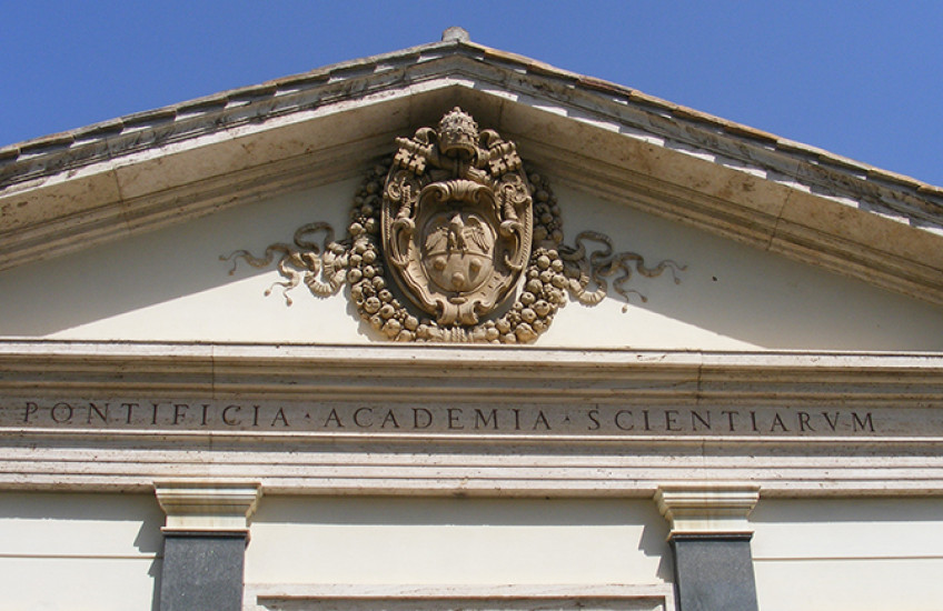 The front of a marble building has an intricate carved seal and the words "Pontificia Academia Scientiarum"