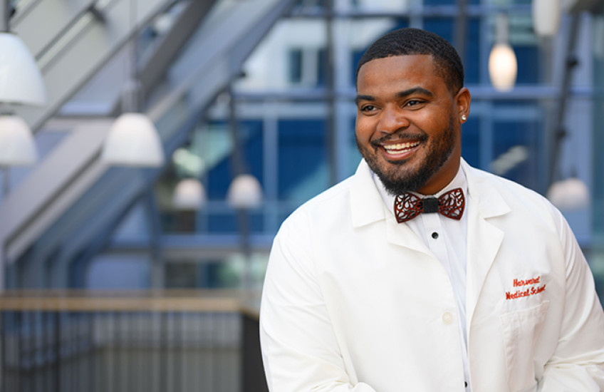 smiling young man in a bow tie and HMS white coat