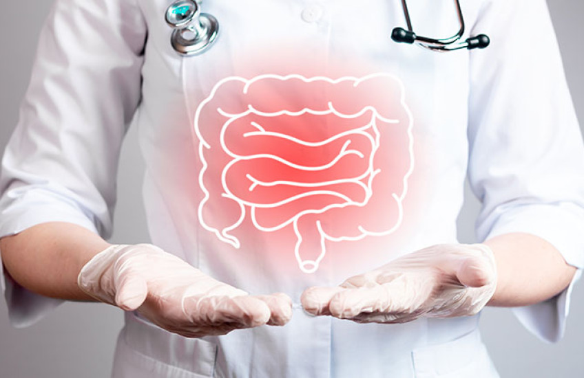 A human figure in a white coat, gloves, and stethoscope points to inflamed colon