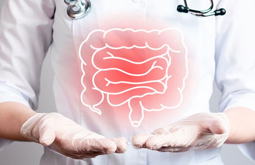 A human figure in a white coat, gloves, and stethoscope points to inflamed colon