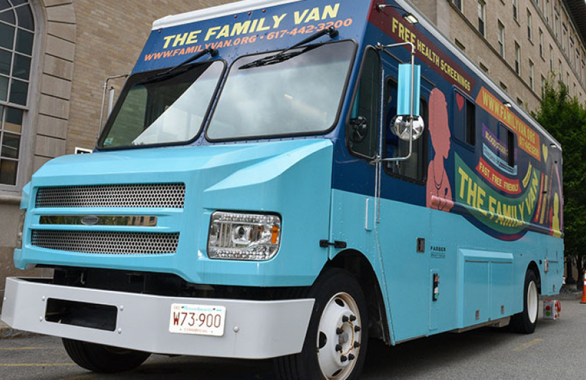 A brightly painted blue mobile clinic van parked on a city street. The side reads “The Family Van” and advertises free health screenings, with the website and phone number displayed above the windshield.