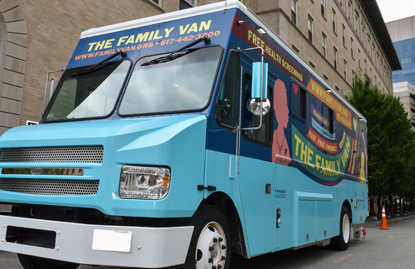 A brightly painted blue mobile clinic van parked on a city street. The side reads “The Family Van” and advertises free health screenings, with the website and phone number displayed above the windshield.