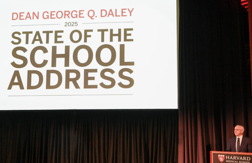 A large white screen that says "Dean George Q. Daley 2025 State of the School Address," next to Dean Daley standing at a lectern