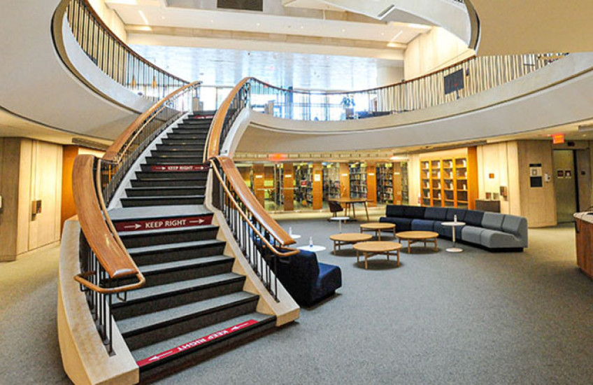 The interior of Countway Library, showing the renovated lower level and a curving staircase leading to upper levels.