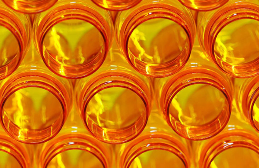 A stack of open orange prescription medicine bottles, glowing with backlight and lightning-shaped highlights.