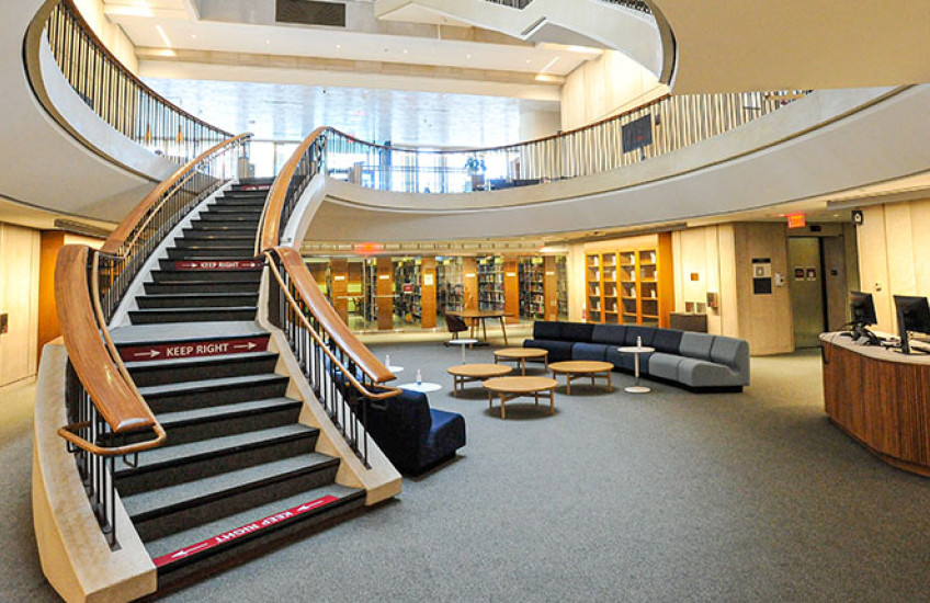 The interior of Countway Library, showing the renovated lower level and a curving staircase leading to upper levels.