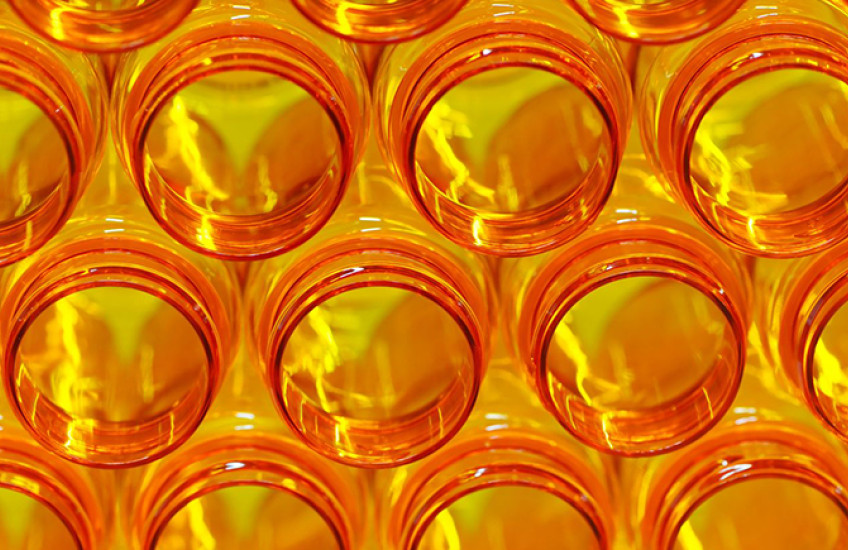 A stack of open orange prescription medicine bottles, glowing with backlight and lightning-shaped highlights.
