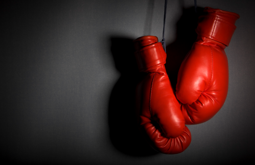A pair of dramatically lit boxing gloves hanging on a wall