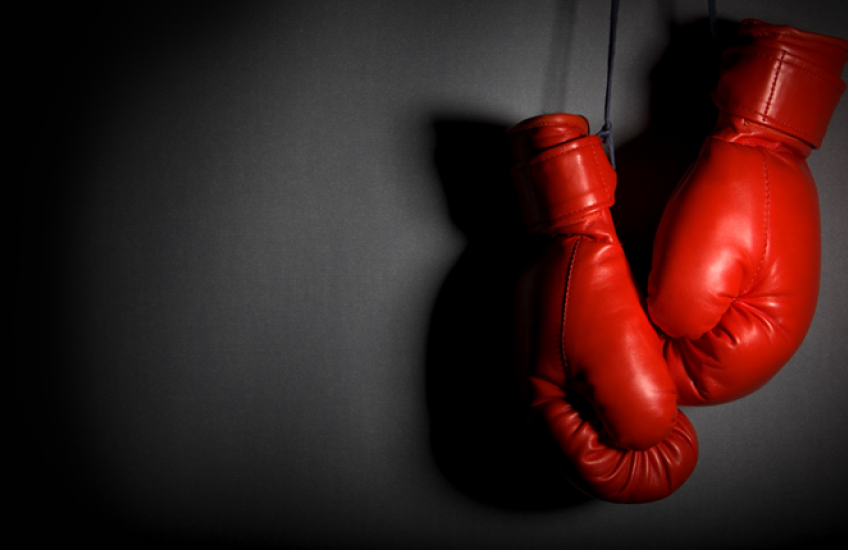 A pair of dramatically lit boxing gloves hanging on a wall