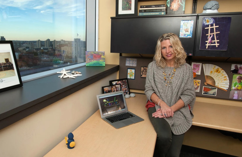 A woman sits at a desk overlooking the Boston skyline