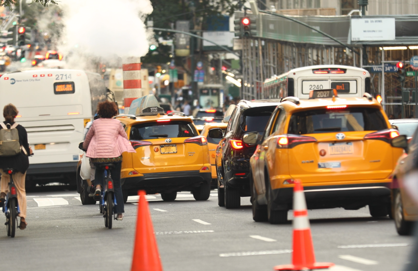 pedestrians, cyclists, and vehicles moving down a busy city street