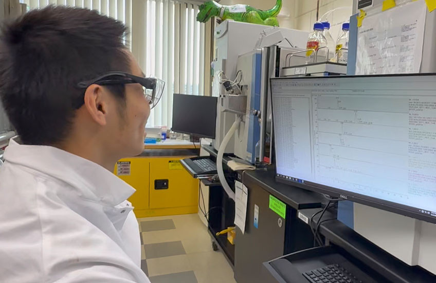 Alan Wong looking at data on a computer screen in a lab.