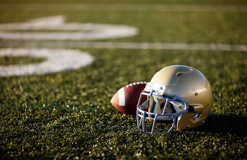 A football helmet and football on an empty field.