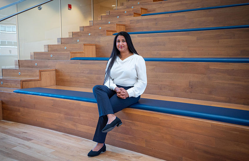 Photo portrait of Arya Rao sitting on a bench in an amphitheater.