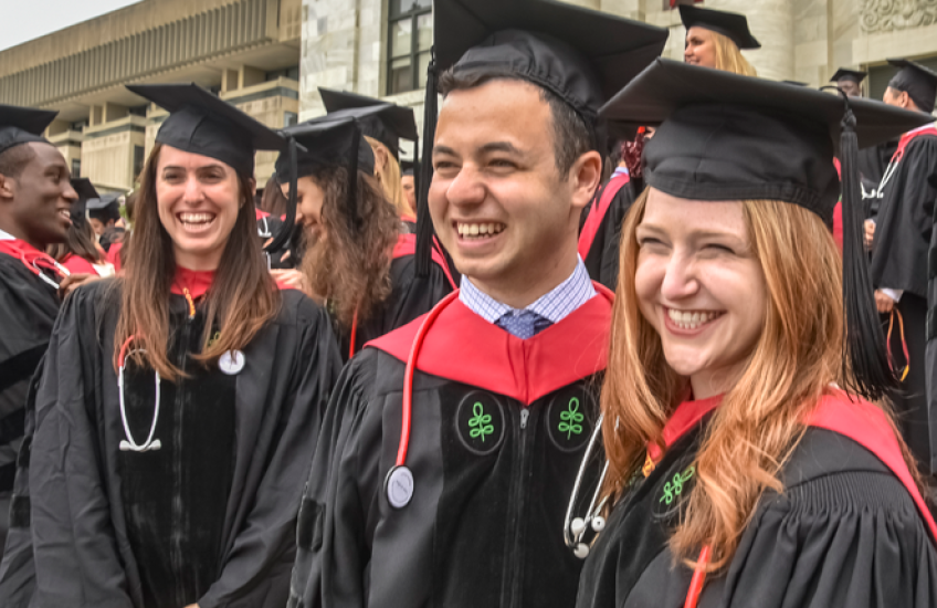 Smiling group of graduates on the steps of the Quad