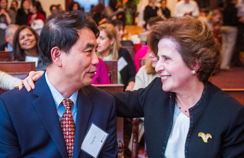 Man and woman smile at each other with hand on shoulder