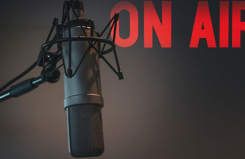 A recording booth microphone with the words "ON AIR" projected on the wall of a studio