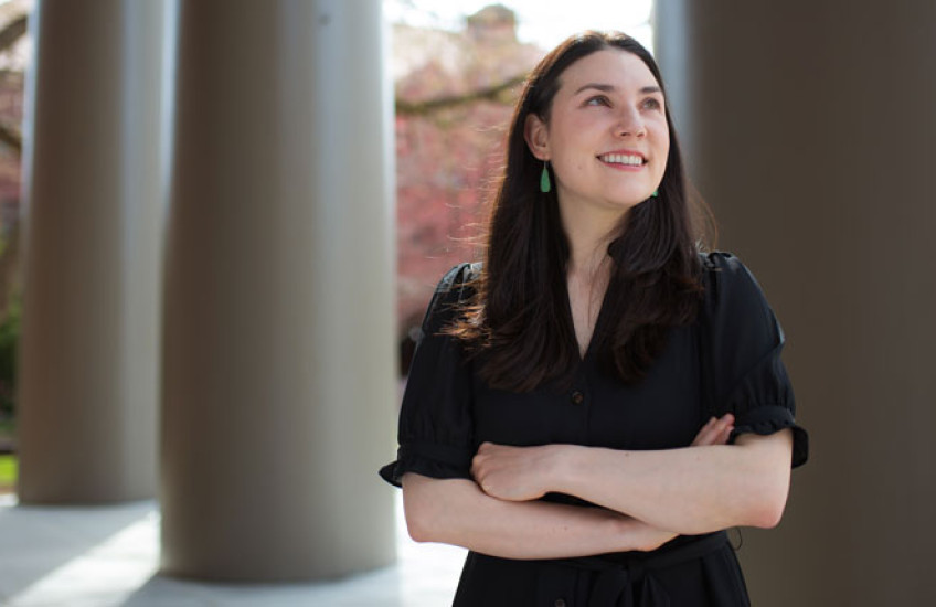 Alyssa Botelho, shot from the waist up in front of columns, looks off into the distance