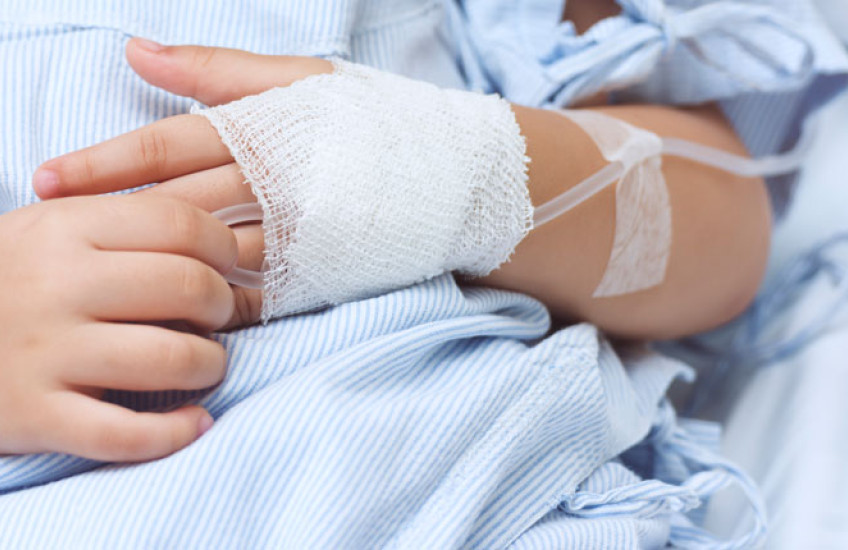 close up shot of a child's hands, one with an IV inserted 