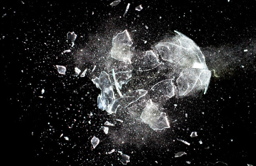 A piece of glass being destroyed against a black background