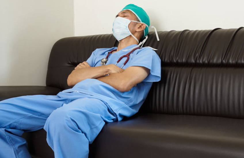 PHOTO OF a doctor in blue scrubs dozing on a couch
