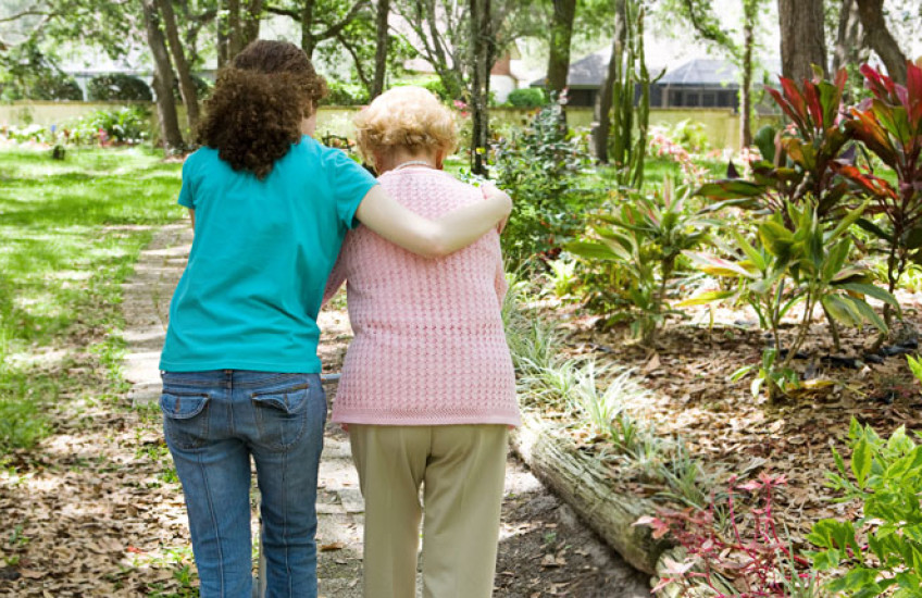 Caregiver walking with an elderly woman, photographed from behind