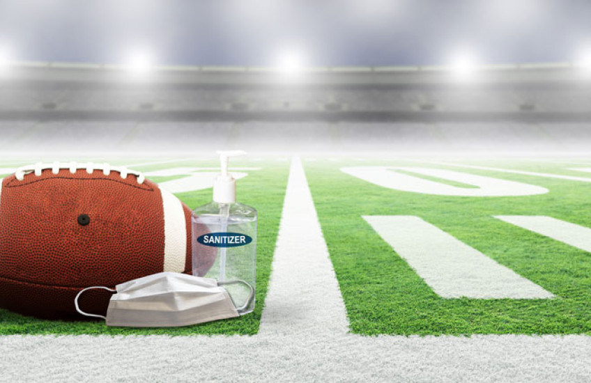 Photo of a football field with a ball, mask, sanitizer